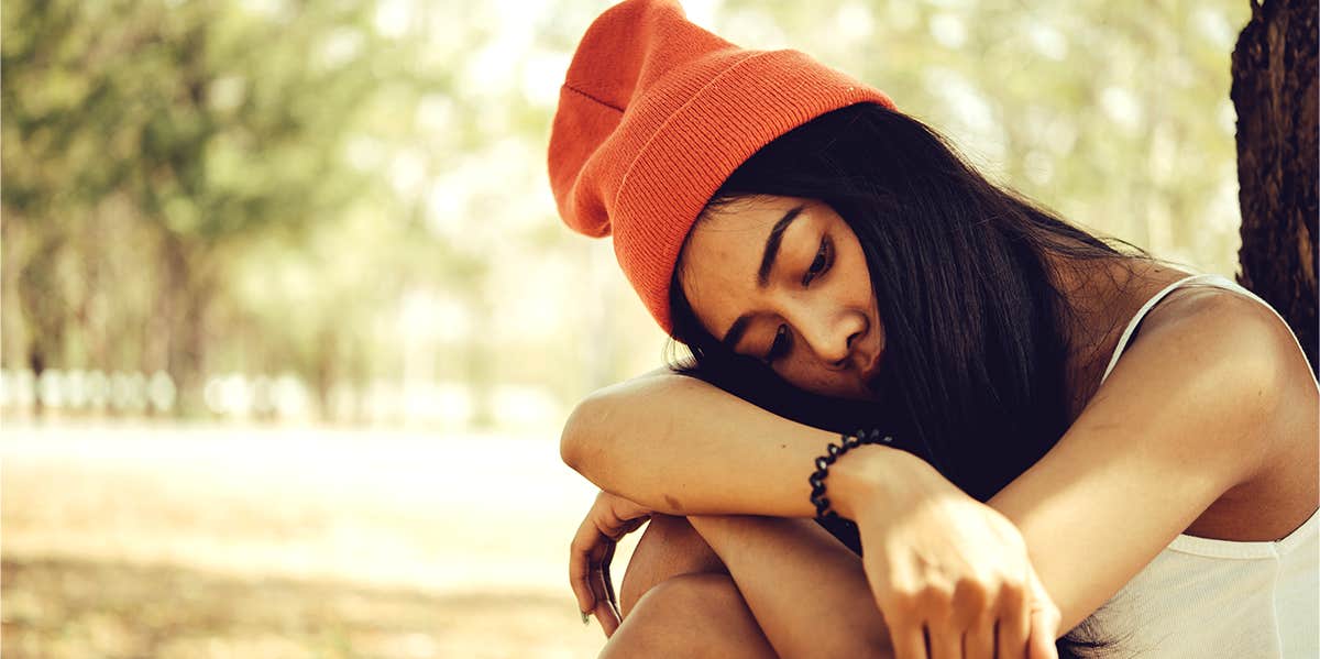 How Understanding The Science Of Broken Heart Syndrome Will Help You Heal Faster sad girl sitting by tree